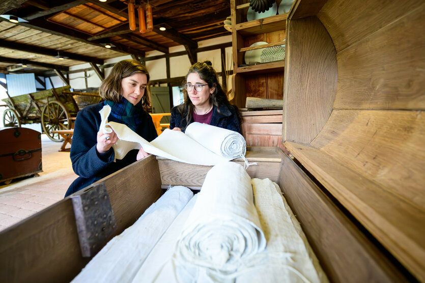 die Kuratorinnen Ruth Stamm (l.) und Sarah Kreiseler wickeln einen Leinenballen ab
