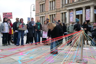 Menschen stehen vor einer Installation mit bunten Fäden