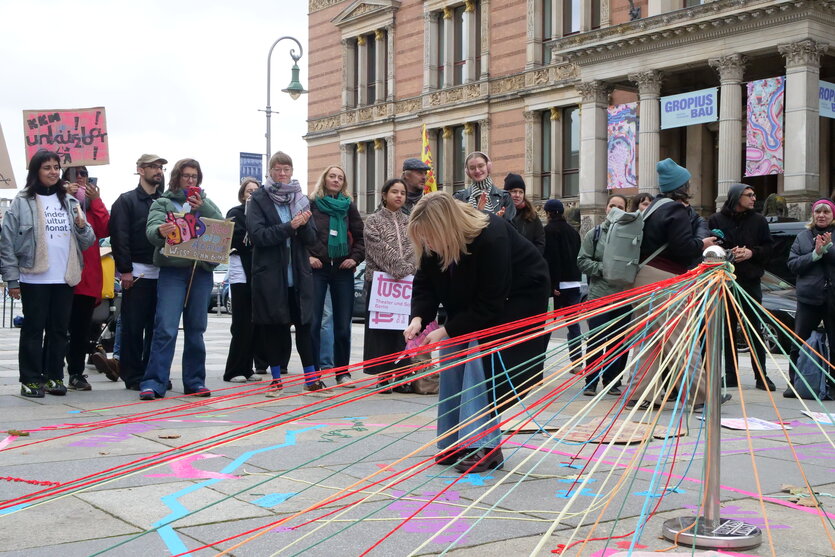 Menschen stehen vor einer Installation mit bunten Fäden