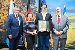 Vier Personen stehen feierlich nebeneinander