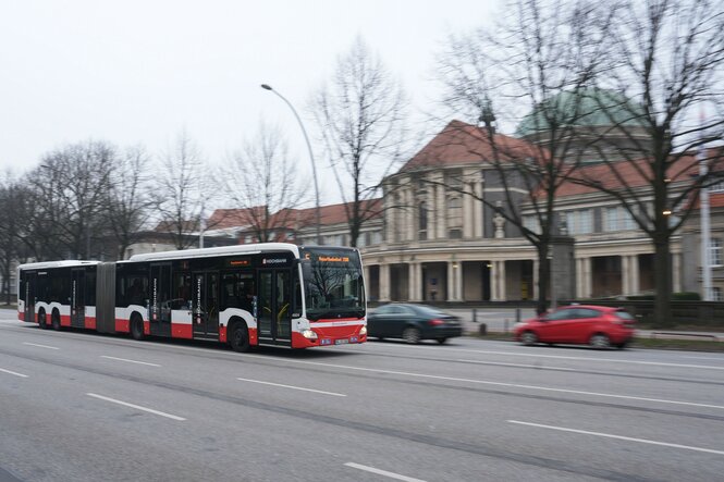 Ein Bus fährt an einem Gebäude mit Säulen-Eingang vorbei