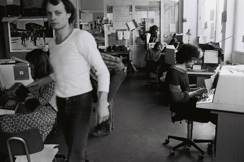 Schwarzweißfoto von einem Büro, ein junger Uli Küsters im weißen T-Shirt läuft durchs Bild