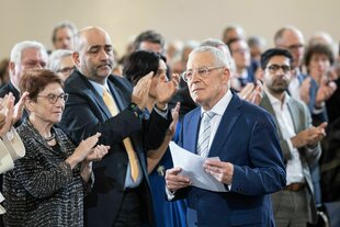 Menschen applaudieren einem älteren Mann
