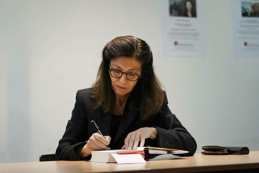 Ursula Krechel sitzt an einem Tisch und schreibt in ein Buch