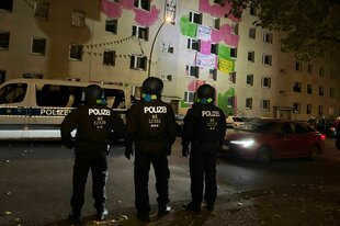 Drei Polizisten vor einem Haus bei Nacht