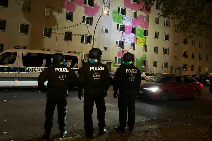 Drei Polizisten vor einem Haus bei Nacht