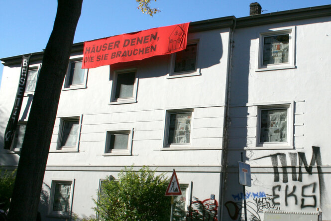 "Häuser denen, die sie brauchen"-Transparent hängt an einer Hauswand