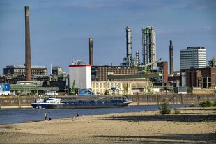 Niedrigwasser auf dem Rhein bei Leverkusen, ein Frachtschiff vor einem Chemiewerk