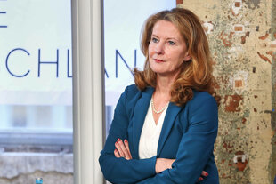 Eine Frau, Heike Raab, steht mit verschrenkten Armen an einer Wand