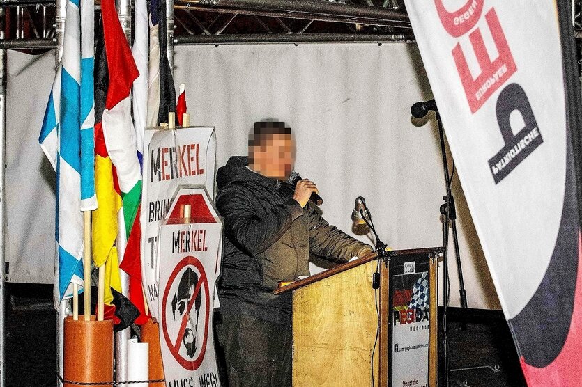 Dan E. als Redner auf einer Bühne mit Pegida-Fahnen