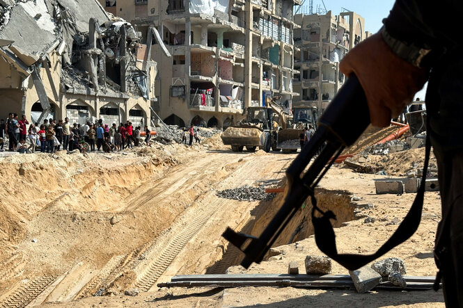 Ein Gewehr in der Hand vor einer Baustelle in Gaza