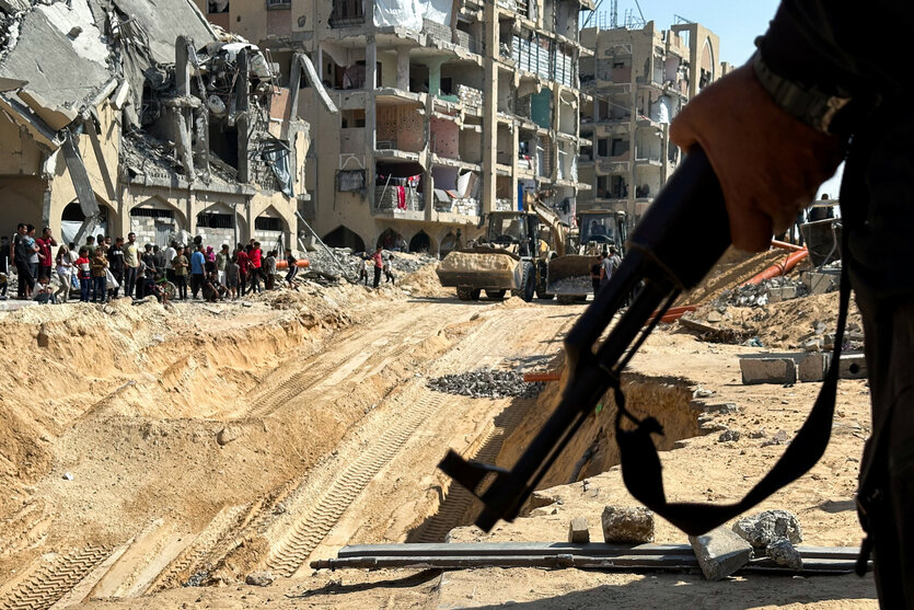 Ein Gewehr in der Hand vor einer Baustelle in Gaza