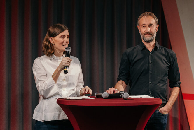 Andreas Marggraf und Aline Lüllmann stehen an einem Rednerpult in der taz Kantine.
