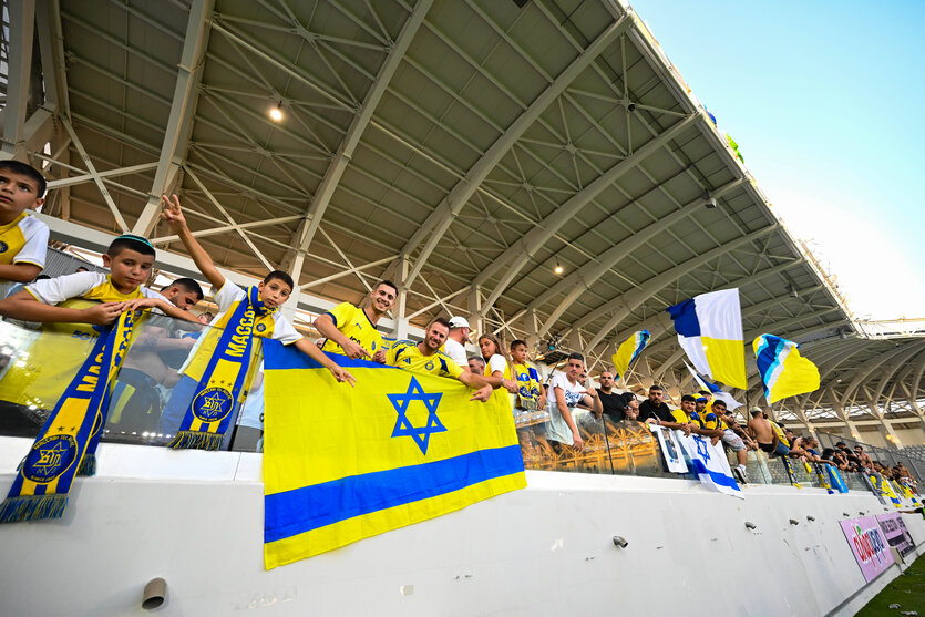 Fans in Blau-gelben Trikost auf einer Stadiontribüne