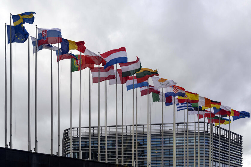 Die Flaggen der EU Mitgliedsstaaten wehen kräftig im Wind vor dem Parlament