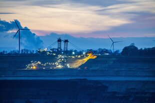 Braunkohletagebau ein Schaufelradbagger, halb angestrahlt in der Abenddämmerung
