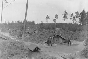 Zwei Männer der US-Armee vor Erdhütten im befreiten Lager Mühldorfer Hart 1945