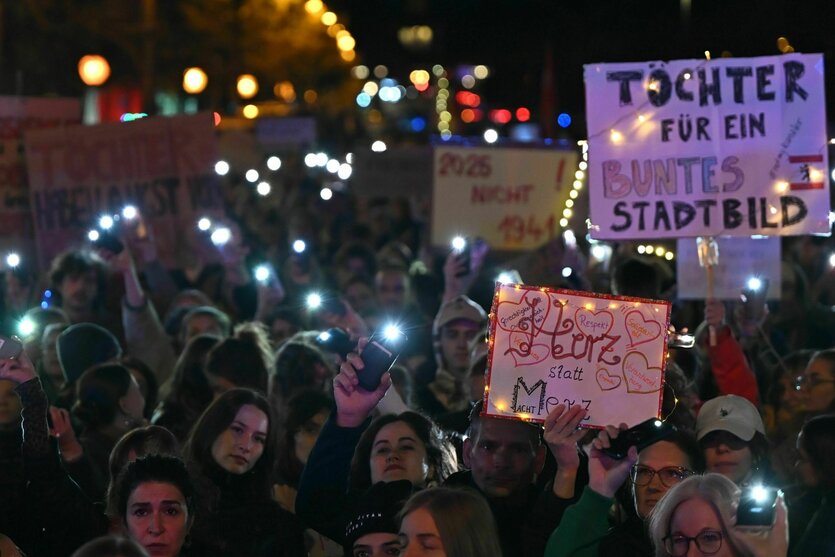 Eine Demo, Menschen halten Handy-Taschenlampen hoch und Schilder mit Aufschriften wie "Herz statt Merz" und "Töchter für ein buntes Stadtbild"