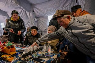 Menschen mit Mobiltelefonen und Ladekabeln in einem Zelt