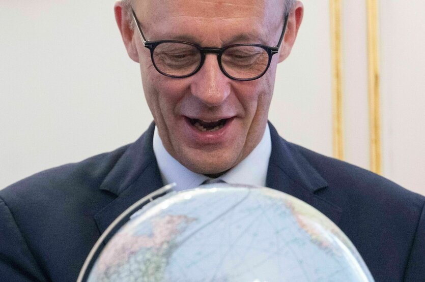 Bundeskanzler Friedrich Merz schaut auf einen Globus