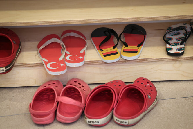 Hausschuhe und Badelatschen in den Farben von Deutschland und der Türkei stehen in einem Regal vor einem Gebetsraum bei einem Pressegespräch in der Bait-ur-Rasheed Moschee in Hamburg-Stellingen.