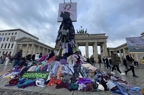 Vor dem Brandenburger Tor ist eine Kunstinstallation aufgebaut. Auf einem Kleiderhügel steht eine Figur, deren Rock aus vielen anderen Kleidungsstücken besteht.