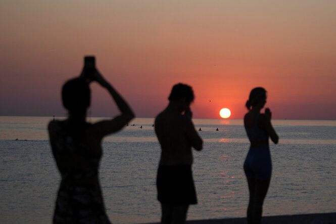 Eine Gruppe von Menschen praktiziert Yoga bei Sonnenaufgang am Strand.