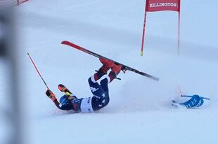 Eine Person auf Skiern stürzt auf der Piste und liegt auf dem Rücken
