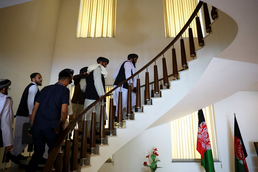 Eine Gruppe Taliban Diplomaten läuft eine geschwungene Treppe hoch