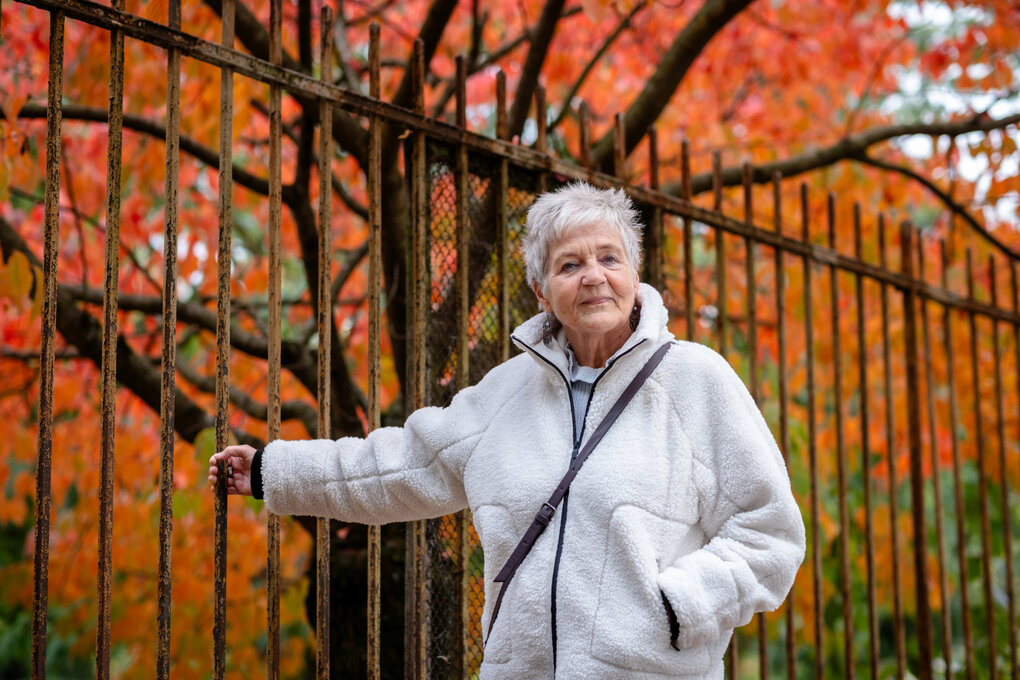 Eine Person steht vor einem herbstlichen Baum.