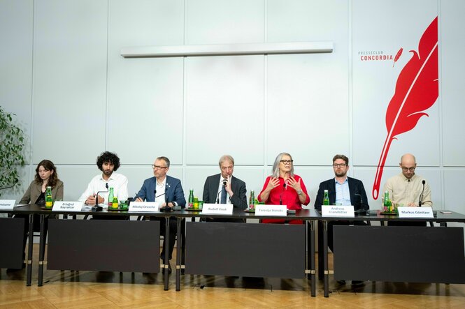 Sieben Personen sitzen nebeneinander