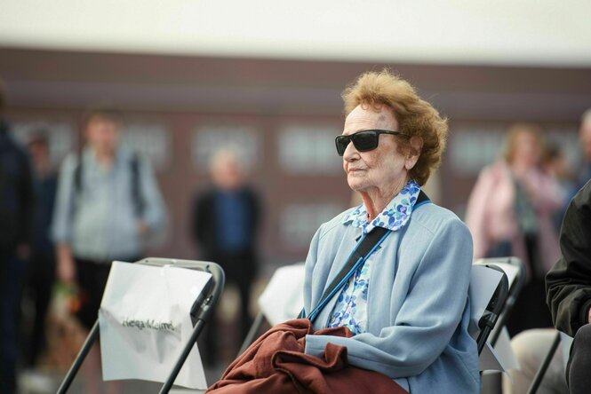 Eine Frau mit Sonnenbrille sitzt aufrecht