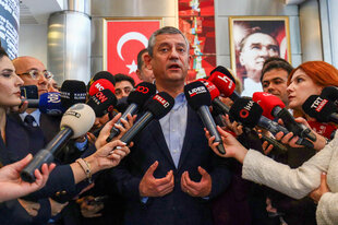 Ein Mann ist umringt von Vertreter:innen der Presse