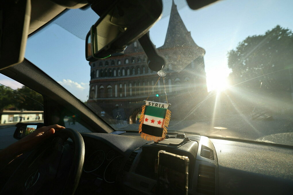 Im Innenraum eines Autos hängt ein Syrien-Fähnchen am Spiegel - Blick in die Sonne