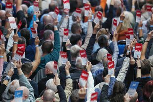 Mitglieder der AfD stimmen mit ihren Stimmkarten „Nein“, wir sehen sie von hinten als eine Menge