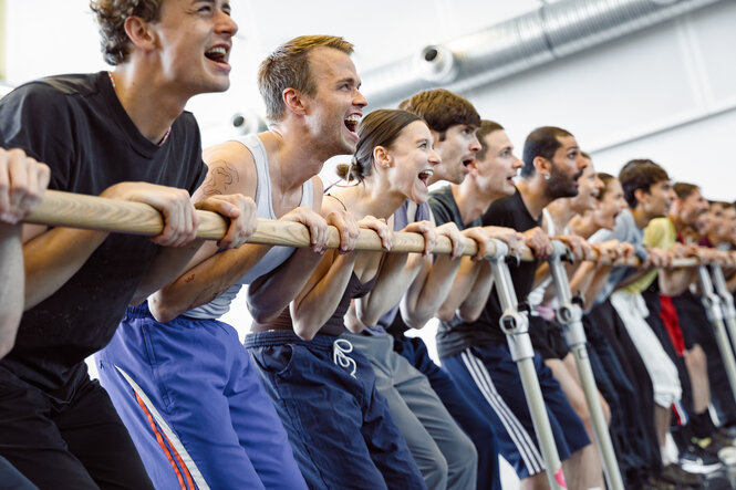 Balletttänzer:innen halten sich an einer Stange fest