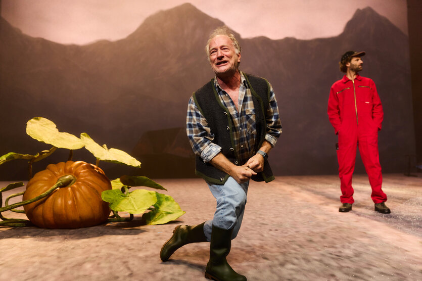 Zwei als Bauern verkleidete Schauspieler, neben ihnen ein riesiger Hokkaido-Kürbis