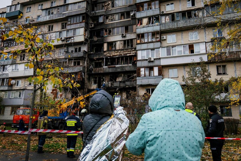 Menschen stehen vor den zerstörten Wohnungen eines Hauses