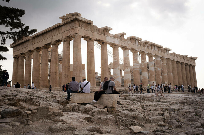 Menschen sitzen vor der Akropolis Ruine