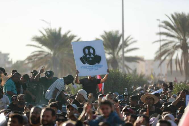 Demonstration in Tunesien, eine Person hält ein Schild mit einer Gasmaske hoch