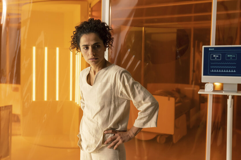 Frau in weiß gekleidet vor orangenem Raum