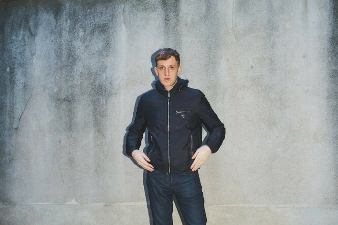 ein junger Mann vor einer grauen Wand