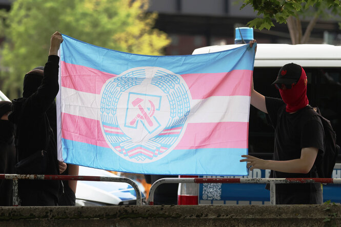 Queere Linke halten eine Fahne mit Hammer und Sichel zu den rechtextremen Demonstranten während des CSD in Berlin am 26. Juli 2025.