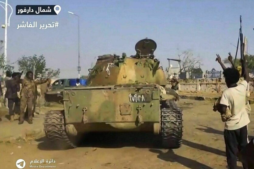 Ein Panzerfahrzeug fährt an Personen auf einer Straße vorbei