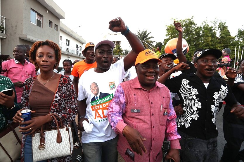 Menschen lachen und freuen sich, einer trägt ein T-Shirt mit dem Konterfei von Alassane Outtara, dem Präsidenten der Elfenbeinküste