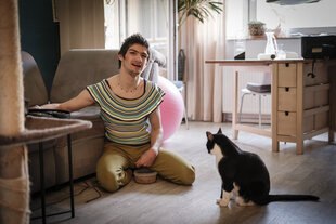 Linn Bade sitzt mit einer Katze auf dem Boden eines Zimmers