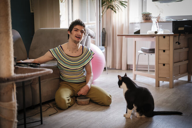 Linn Bade sitzt mit einer Katze auf dem Boden eines Zimmers