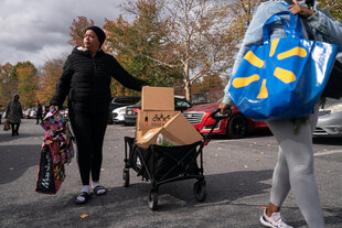 Zwei Personen ziehen einen Bollerwagen mit Kartons eine Straße entlang