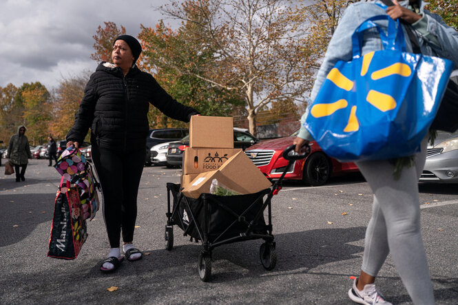 Zwei Personen ziehen einen Bollerwagen mit Kartons eine Straße entlang