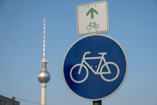 Ein Strassenschild mit Fahrrad, dahinter der Fernsehturm